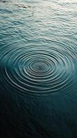 Ripples expanding in dark water under rain creating a calm and tranquil atmosphere photo