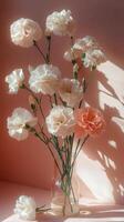 Delicate bouquet of white and pink carnations in glass vase against soft pink background photo