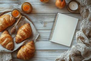 Freshly baked croissants with honey and citrus fruits on a rustic table in soft morning light photo