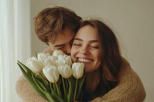 Young couple smiling together while holding white tulips in a cozy indoor setting photo