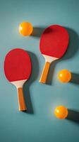 Two red table tennis paddles and a yellow ball on a blue background in a minimalistic arrangement photo