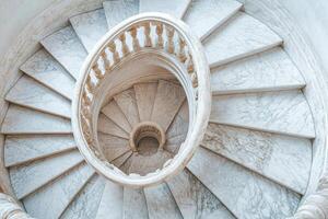 Elegant spiral staircase captured from above in a historic building with intricate design details photo