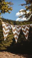 Decorative gold and white bunting strung between trees at a sunny outdoor gathering photo
