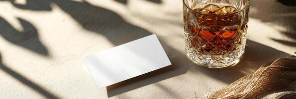 A glass of amber liquid rests on a marble surface illuminated by soft sunlight photo