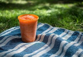 Refreshing orange drink on a blue striped cloth in a sunny outdoor setting photo