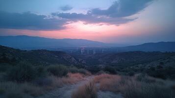 Sunset over rolling hills with wind turbines and a winding dirt road in the countryside photo