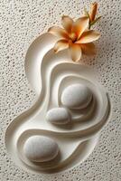 Tranquil arrangement of stones and flowers on textured sand pattern in a serene setting photo