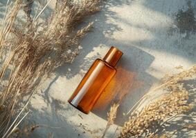 Glass bottle resting on a textured surface surrounded by dried plants in natural lighting photo
