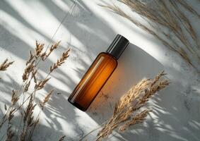 Glass bottle resting on a textured surface surrounded by dried plants in natural lighting photo