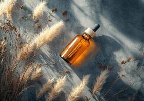 Glass bottle resting on a textured surface surrounded by dried plants in natural lighting photo