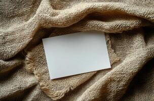 Blank card resting on textured burlap fabric creates a simple and rustic background composition photo
