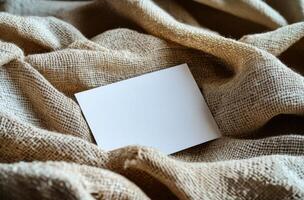 Blank card resting on textured burlap fabric creates a simple and rustic background composition photo