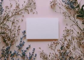 Blank card surrounded by blooming flowers and green leaves on a soft pink background photo