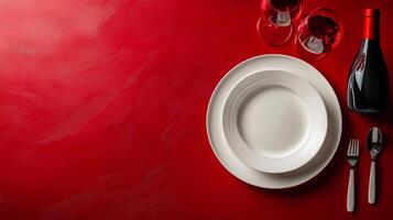 Elegant dining setup with wine glasses, plates, and a bottle against a rich red background photo
