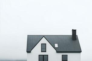 A minimalist white house with a sleek roof design against a cloudy sky in a serene landscape photo