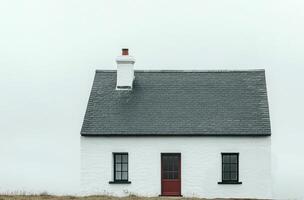 A minimalist white house with a sleek roof design against a cloudy sky in a serene landscape photo