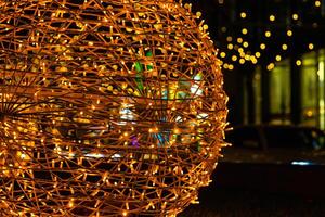 Closeup of intertwined golden string lights. Abstract view of crisscrossing glowing yellow LED garland with small bright bulbs, radiating light against a dark background. Berlin, Germany. Copy space photo