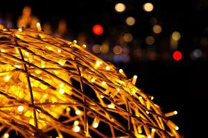 Closeup of intertwined golden string lights. Abstract view of crisscrossing glowing yellow LED garland with small bright bulbs, radiating light against a dark background. Berlin, Germany. Copy space photo