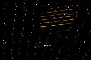 Abstract view of light strings hanging against a city building in the nighttime. Twinkling lights in the night, highlighting a dimly lit building in the background. Germany, Berlin photo