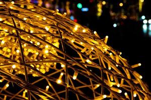 Closeup of intertwined golden string lights. Abstract view of crisscrossing glowing yellow LED garland with small bright bulbs, radiating light against a dark background. Berlin, Germany. Copy space photo