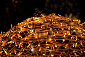 Closeup of intertwined golden string lights. Abstract view of crisscrossing glowing yellow LED garland with small bright bulbs, radiating light against a dark background. Berlin, Germany. Copy space photo