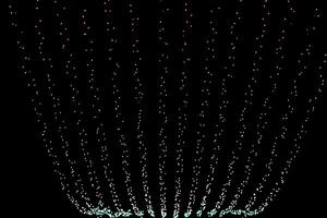 Festive light strings hanging in the sky and glowing in the dark night city sky. Twinkling lights in contrast with black background. Holiday urban illumination. Copy space photo