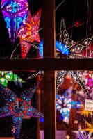Rain speckled window showcasing illuminated colorful star lanterns glowing at Berlin Christmas market. Festive winter atmosphere with vibrant holiday lights photo