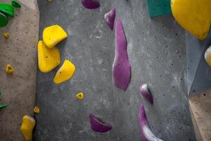 Closeup of colorful climbing holds on artificial rock wall in gym photo