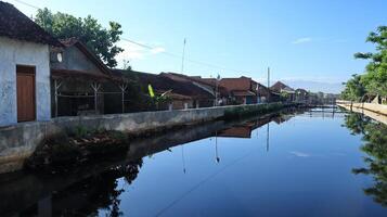 River embankment in the middle of a settlement to prevent flooding and tidal flooding photo