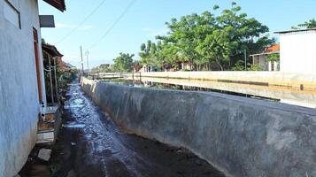 River embankment in the middle of a settlement to prevent flooding and tidal flooding photo