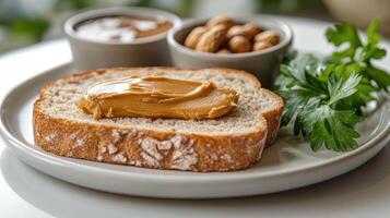 Whole grain bread with peanut butter accompanied by nuts and green herbs on a plate photo