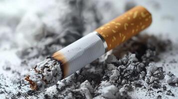 A partially burned cigarette rests in a pile of ash, capturing the aftermath of smoking photo