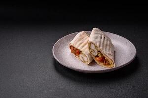 Roll with pita, meat, tomatoes, cheese, sauce, salt and spices photo