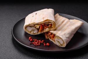 Roll with pita, meat, tomatoes, cheese, sauce, salt and spices photo