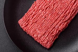 Fresh raw ground beef with salt, spices and herbs photo