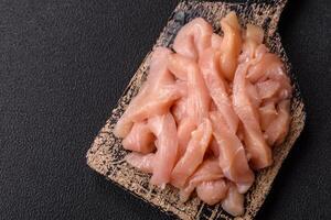 Raw chicken fillet cut into strips with spices and herbs photo
