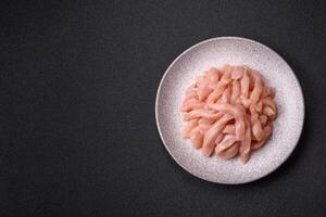 Raw chicken fillet cut into strips with spices and herbs photo