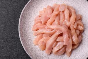 Raw chicken fillet cut into strips with spices and herbs photo