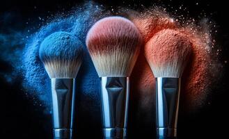 Colorful makeup brushes with vibrant powder clouds. Three makeup brushes stand with colorful powders, creating dynamic clouds of blue, pink, and orange against a dark background. photo