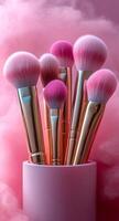 Vibrant pink makeup brushes in a sleek holder. A collection of pink and gold makeup brushes stands in a stylish holder against a soft pink background, adding a pop of color. photo