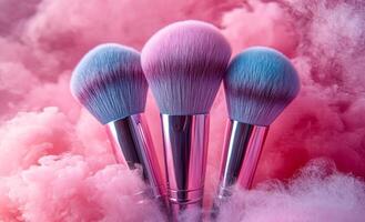 Colorful brushes on fluffy cloud backdrop. Three vibrant makeup brushes are surrounded by a soft pink and blue cloud, creating a whimsical, artistic atmosphere. photo