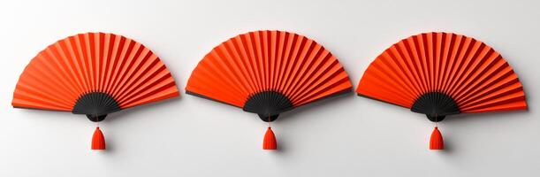 Red folding fans on wall display. Three beautifully crafted red folding fans hang elegantly on a white wall, showcasing their intricate design and vibrant color. photo