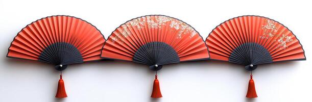 Elegant decorative fans arranged in a row. A group of three red decorative fans showcases intricate designs, featuring black accents and tassels, creating a stunning display. photo
