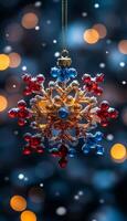 A snowflake ornament hangs from a string. The snowflake is made of glass and has a blue, red, and gold design. The background is blurry, giving the image a dreamy, ethereal quality photo