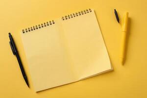 folded craft paper felt tip pen near blank spiral notepad yellow background photo
