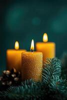 Burning advent candles with evergreen branches and pine cones on green background photo
