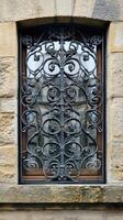 Old european window reflecting building with ornate iron grillwork photo