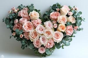 Heart shaped bouquet of pink roses and eucalyptus lying on white background photo