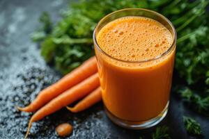 Glass of freshly squeezed carrot juice with carrots on dark background photo