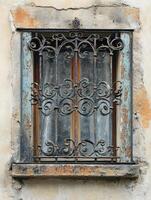 Old window with ornate iron grill showing age and weathering photo